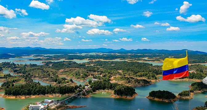 View of the Guatape dam with the Colombian flag waving, Guatape, Antioquia, Colombia. Adobe Stock